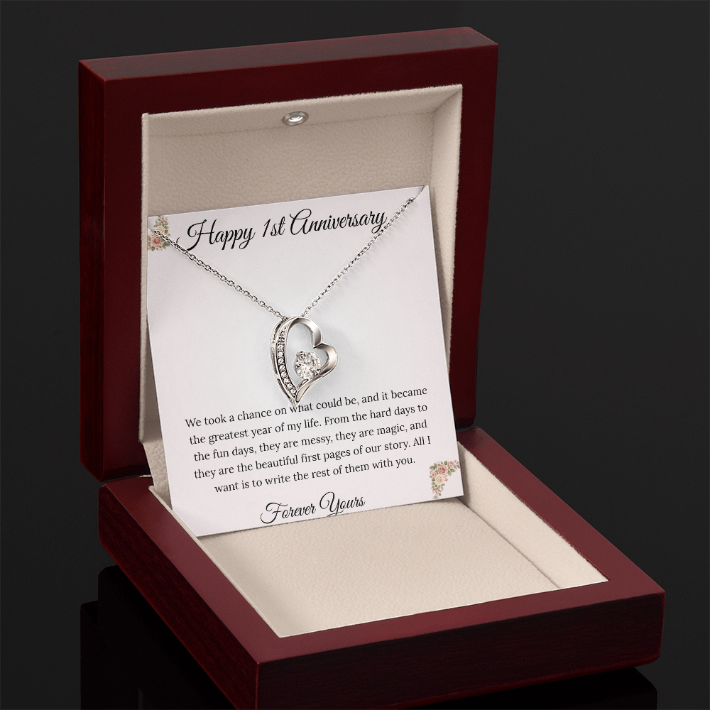 1st Anniversary gift for wife featuring a Forever Love heart necklace inside a luxury mahogany LED box. The pendant rests on a soft blush message card with blue floral corners and a romantic "messy and magic" quote
