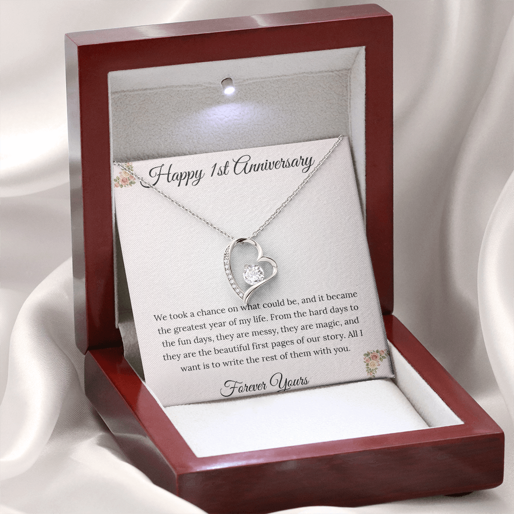 1st Anniversary gift for wife featuring a Forever Love heart necklace inside a luxury mahogany LED box. The pendant rests on a soft blush message card with blue floral corners and a romantic "messy and magic" quote