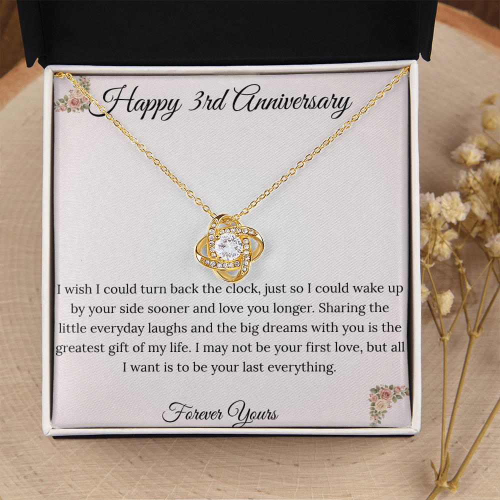 3rd Anniversary gift for wife featuring a brilliant Love Knot necklace inside a luxury mahogany LED box. The pendant rests on a soft blush message card with warm pink floral corners and a romantic "last everything" quote