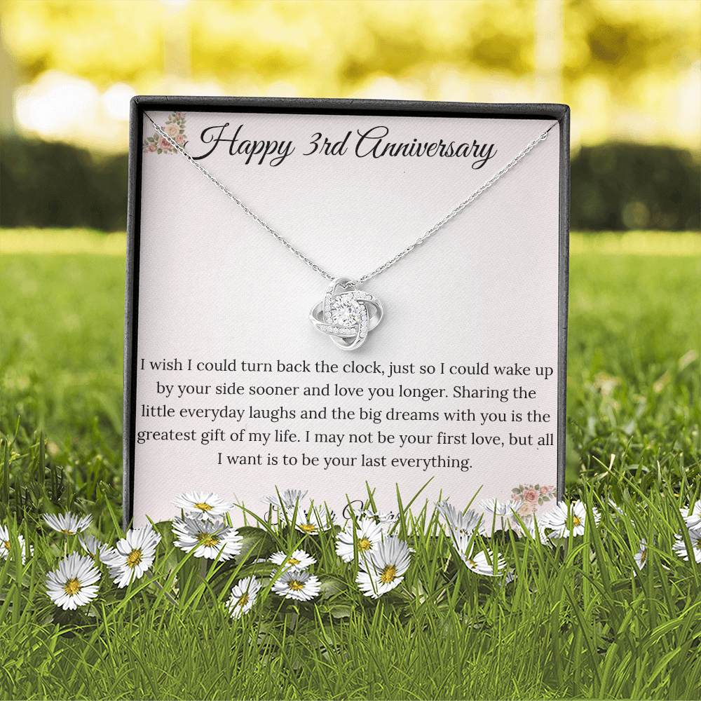 3rd Anniversary gift for wife featuring a brilliant Love Knot necklace inside a luxury mahogany LED box. The pendant rests on a soft blush message card with warm pink floral corners and a romantic "last everything" quote