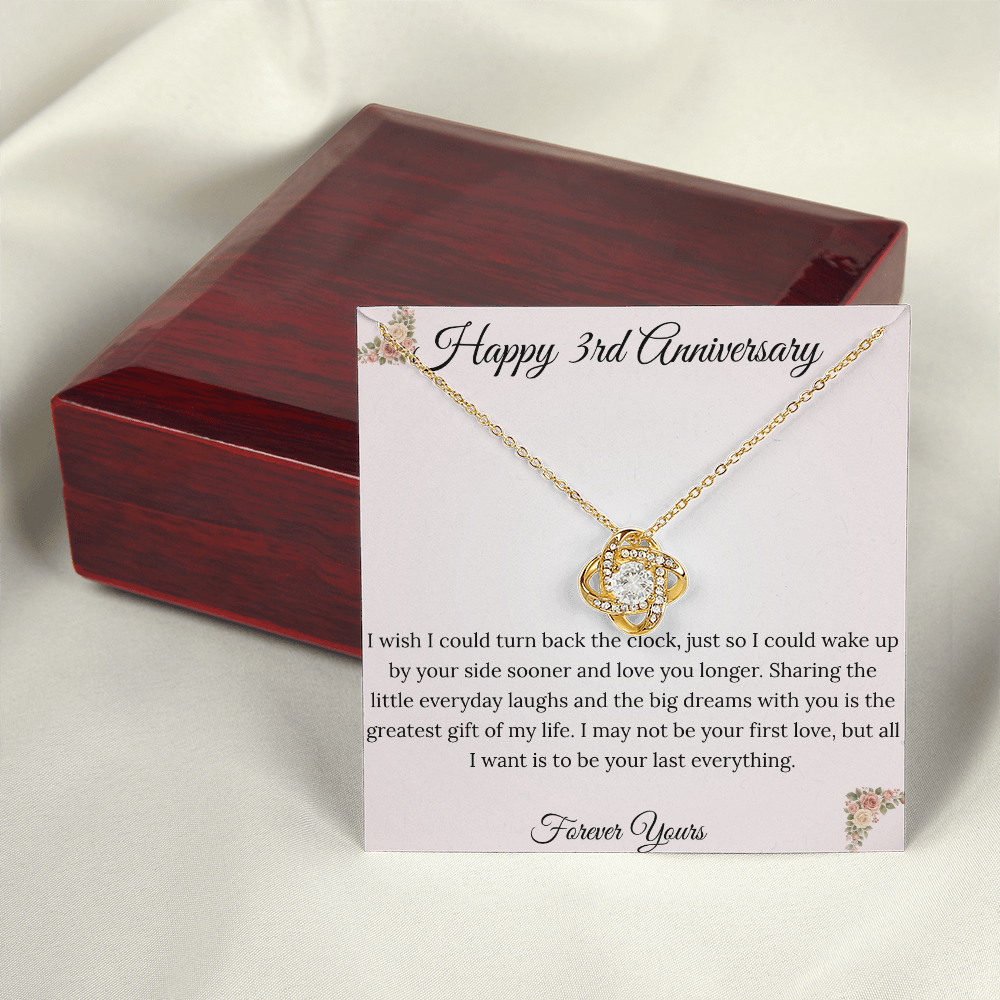 3rd Anniversary gift for wife featuring a brilliant Love Knot necklace inside a luxury mahogany LED box. The pendant rests on a soft blush message card with warm pink floral corners and a romantic "last everything" quote
