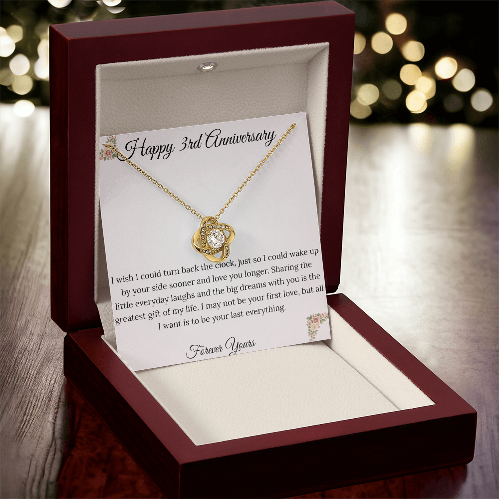 3rd Anniversary gift for wife featuring a brilliant Love Knot necklace inside a luxury mahogany LED box. The pendant rests on a soft blush message card with warm pink floral corners and a romantic "last everything" quote