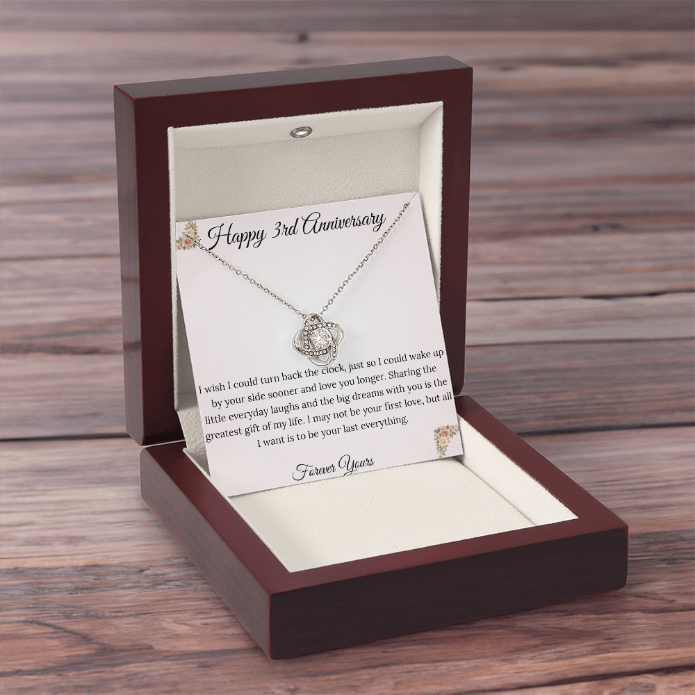 3rd Anniversary gift for wife featuring a brilliant Love Knot necklace inside a luxury mahogany LED box. The pendant rests on a soft blush message card with warm pink floral corners and a romantic "last everything" quote