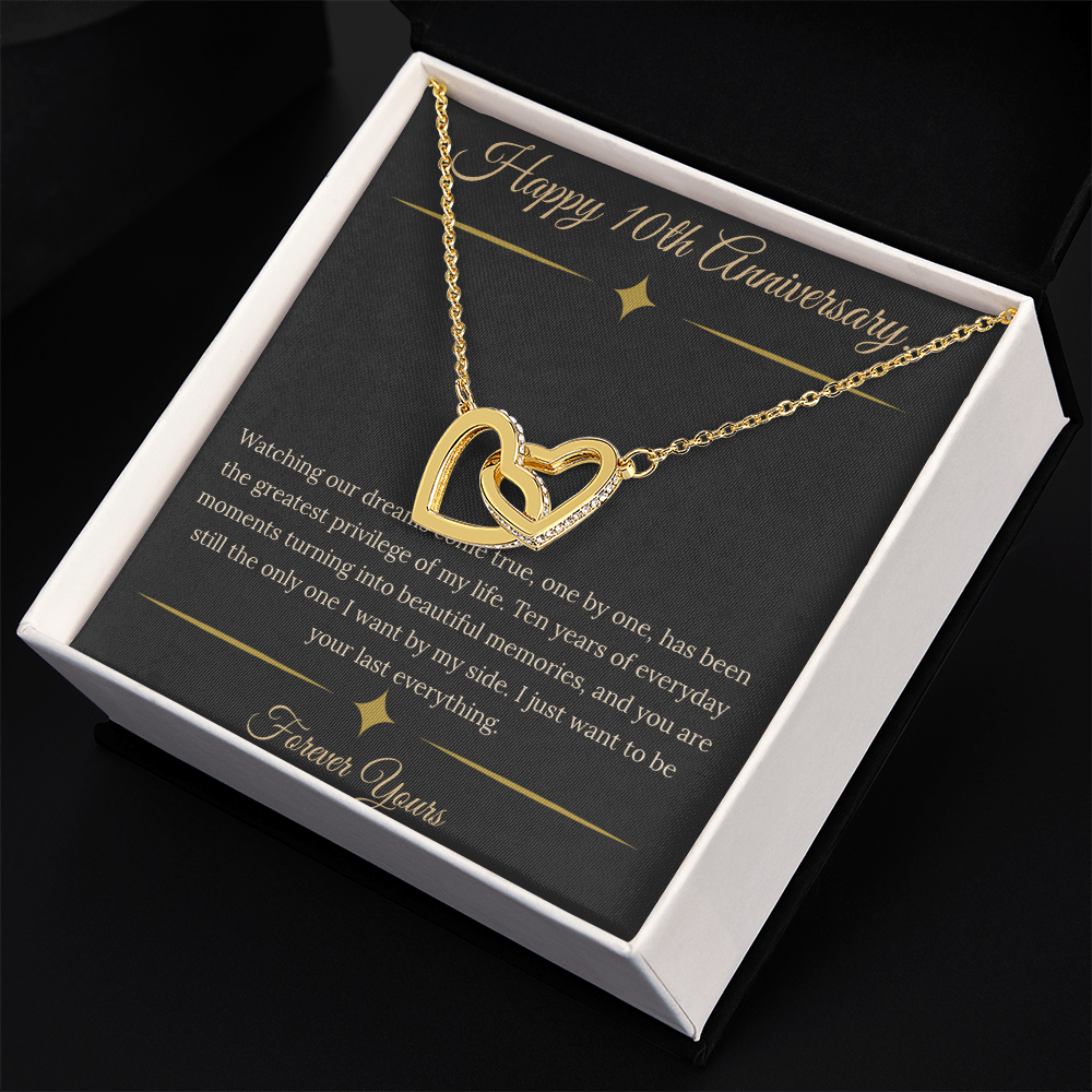 10th Anniversary gift for wife featuring a silver and rose gold interlocking hearts necklace inside a luxury mahogany LED box. The necklace rests on a dark premium message card with gold dividers and a romantic quote about dreams coming true.
