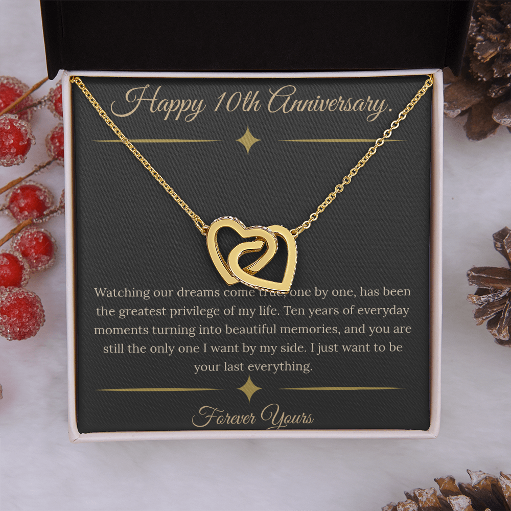 10th Anniversary gift for wife featuring a silver and rose gold interlocking hearts necklace inside a luxury mahogany LED box. The necklace rests on a dark premium message card with gold dividers and a romantic quote about dreams coming true.
