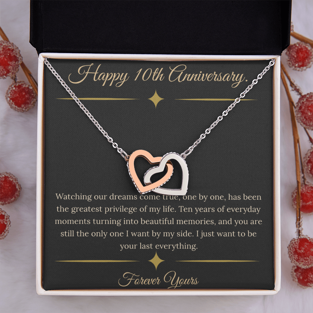10th Anniversary gift for wife featuring a silver and rose gold interlocking hearts necklace inside a luxury mahogany LED box. The necklace rests on a dark premium message card with gold dividers and a romantic quote about dreams coming true.