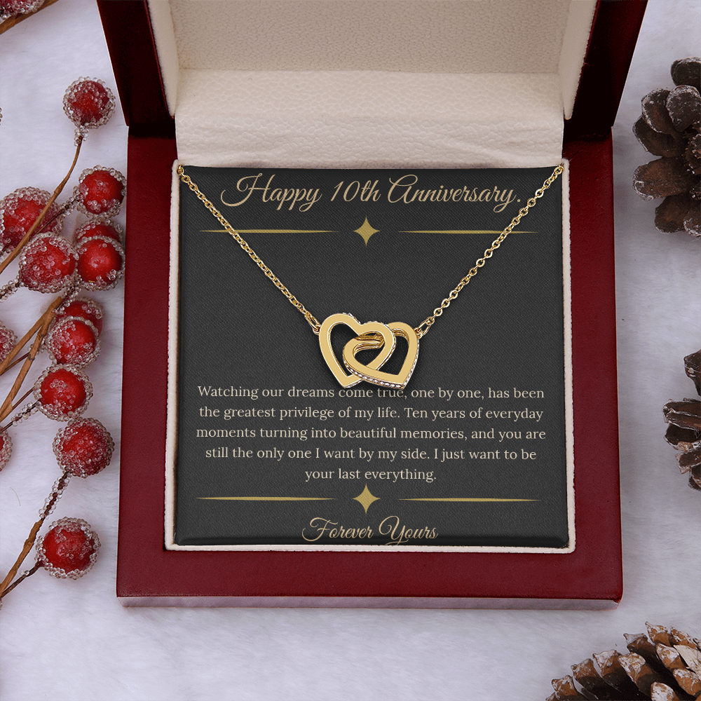 10th Anniversary gift for wife featuring a silver and rose gold interlocking hearts necklace inside a luxury mahogany LED box. The necklace rests on a dark premium message card with gold dividers and a romantic quote about dreams coming true.