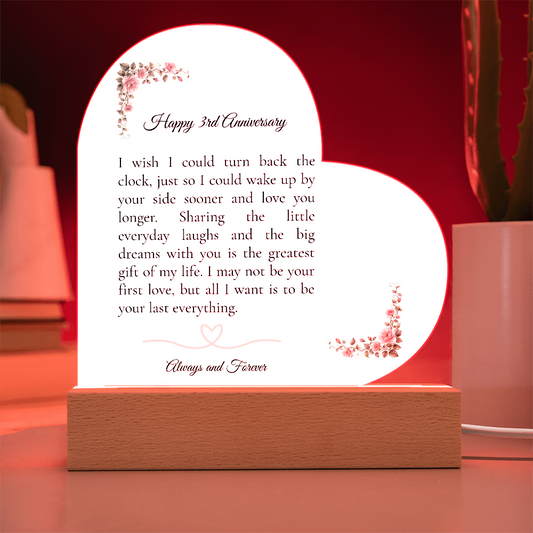 Heart shaped clear acrylic 3rd anniversary gift for wife on a glowing purple LED wooden base.
