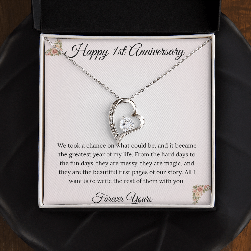 1st Anniversary gift for wife featuring a Forever Love heart necklace inside a luxury mahogany LED box. The pendant rests on a soft blush message card with blue floral corners and a romantic "messy and magic" quote