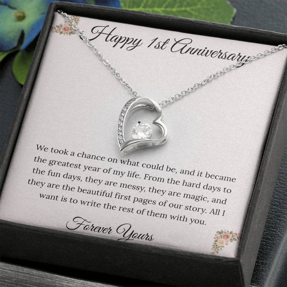 1st Anniversary gift for wife featuring a Forever Love heart necklace inside a luxury mahogany LED box. The pendant rests on a soft blush message card with blue floral corners and a romantic "messy and magic" quote