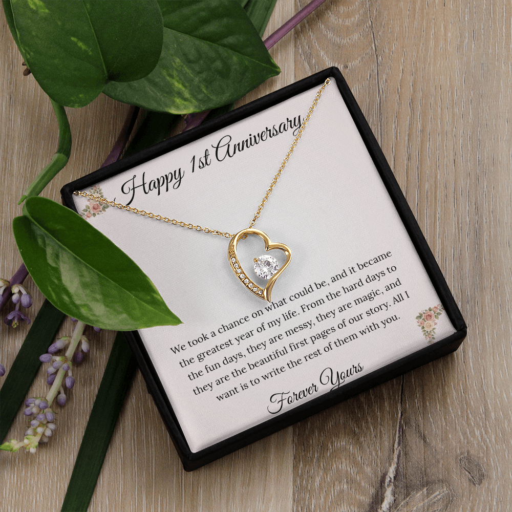 1st Anniversary gift for wife featuring a Forever Love heart necklace inside a luxury mahogany LED box. The pendant rests on a soft blush message card with blue floral corners and a romantic "messy and magic" quote