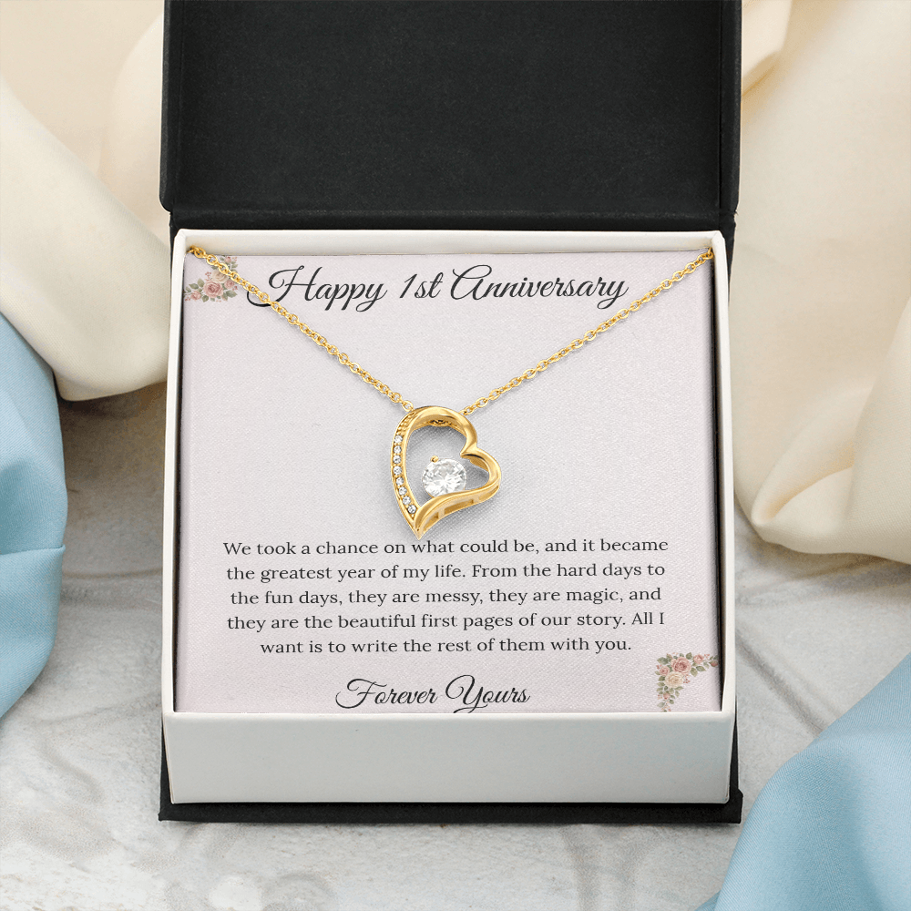 1st Anniversary gift for wife featuring a Forever Love heart necklace inside a luxury mahogany LED box. The pendant rests on a soft blush message card with blue floral corners and a romantic "messy and magic" quote
